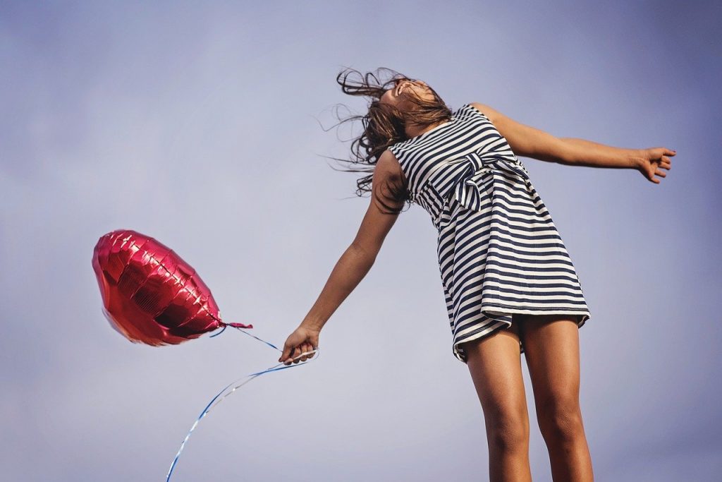 gesunde Frau mit rotem Ballon in der Hand