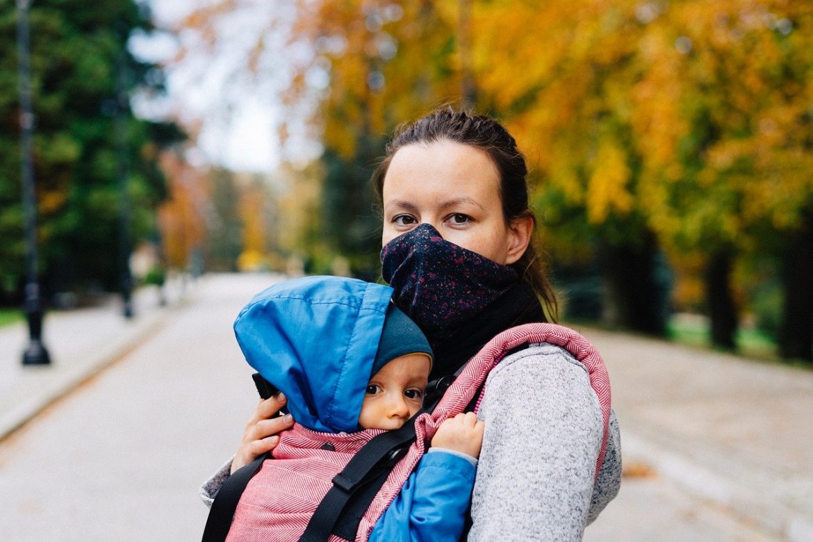 Frau mit Baby im Arm und Maske