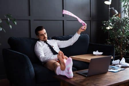 Fauler Geschäftsmann sitzt motivationslos auf dem Sofa und ist trotzdem erfolgreich